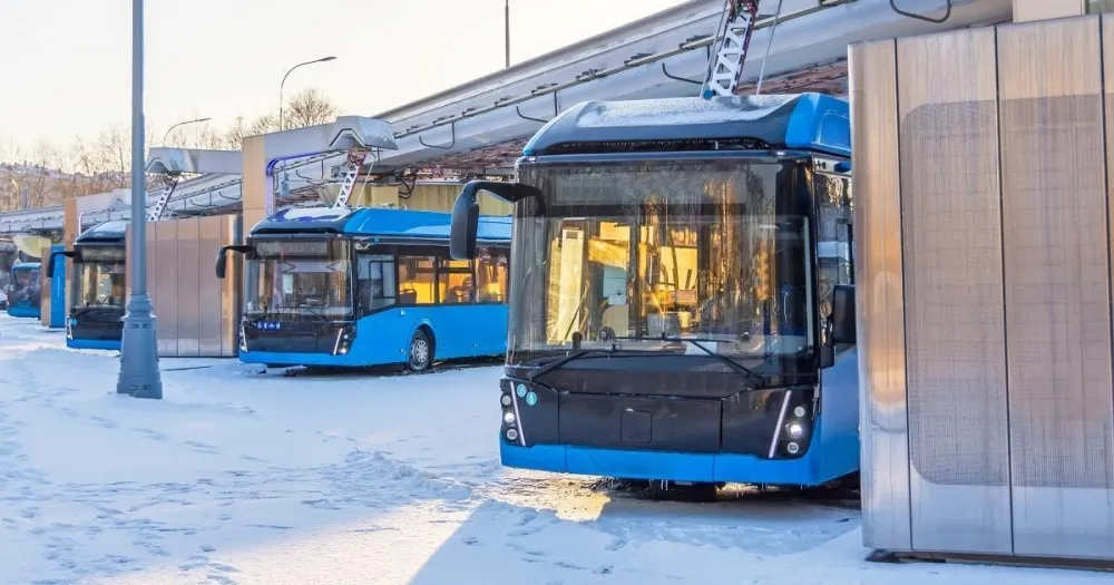 Electric buses at a snowy depot charging in winter